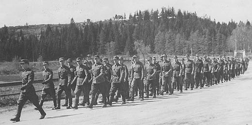 Sotilaspukuiset miehet marssijonossa.